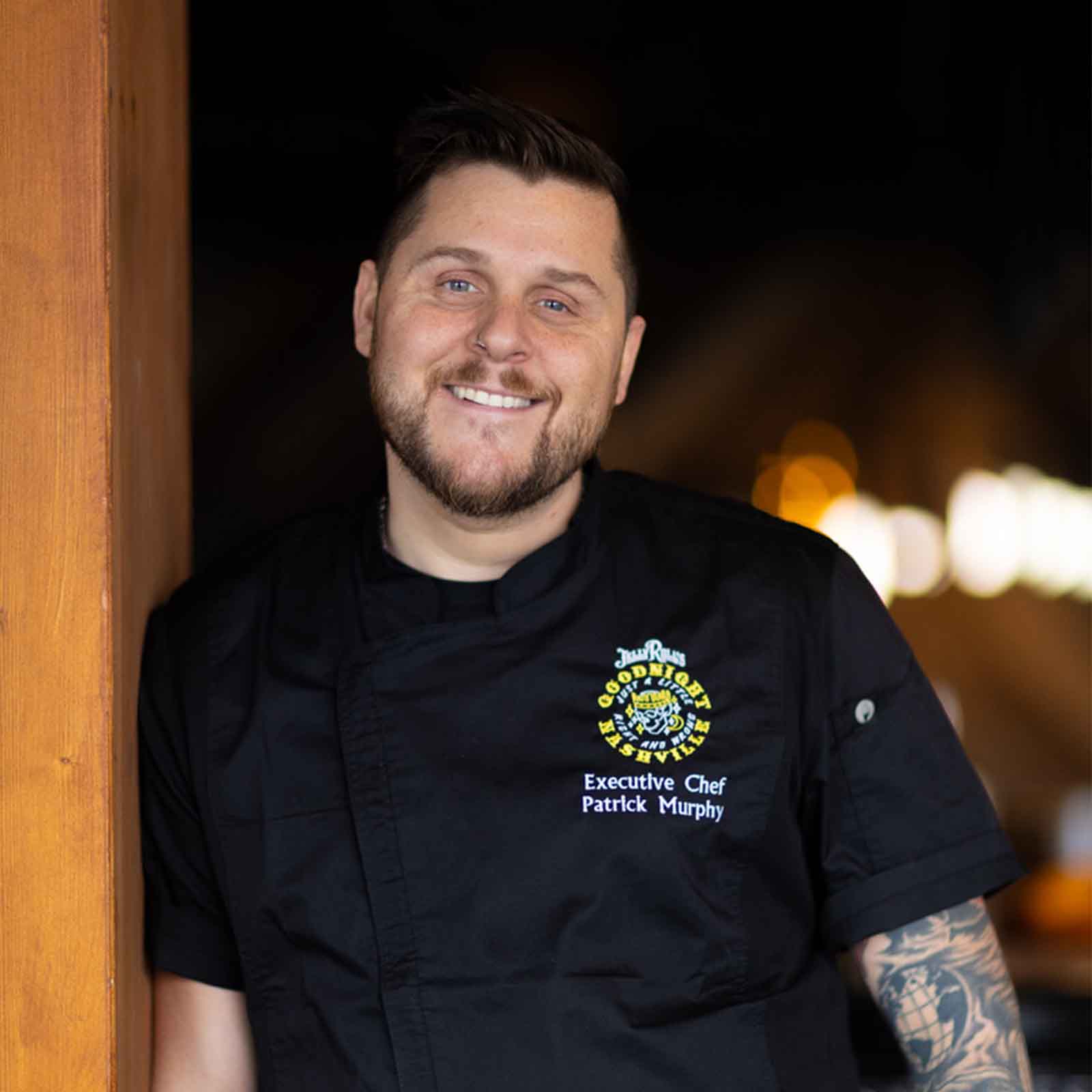 The image shows an executive chef, Patrick Murphy, smiling and wearing a black chef