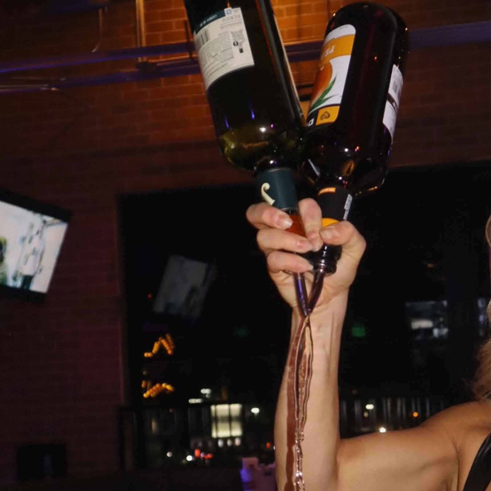 A bartender pouring drinks from multiple bottles at once.