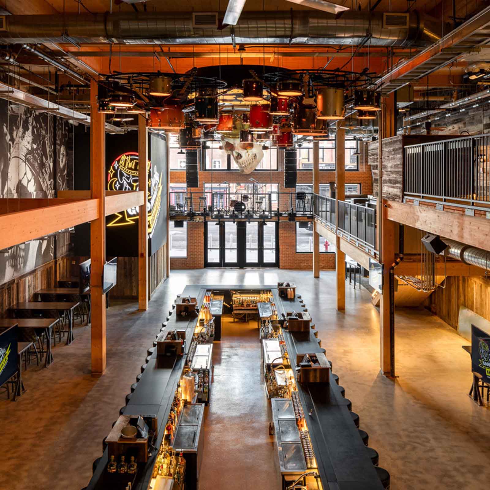 A spacious bar venue with two long bars, illuminated with warm light, and an overhead view showing rows of chairs and tables