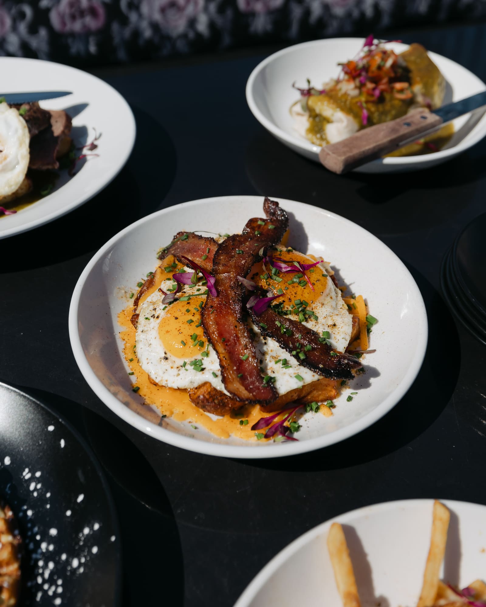 Delectable breakfast dishes featuring a variety of savory and flavorful options including an omelette topped with extra crispy bacon and seasoning.