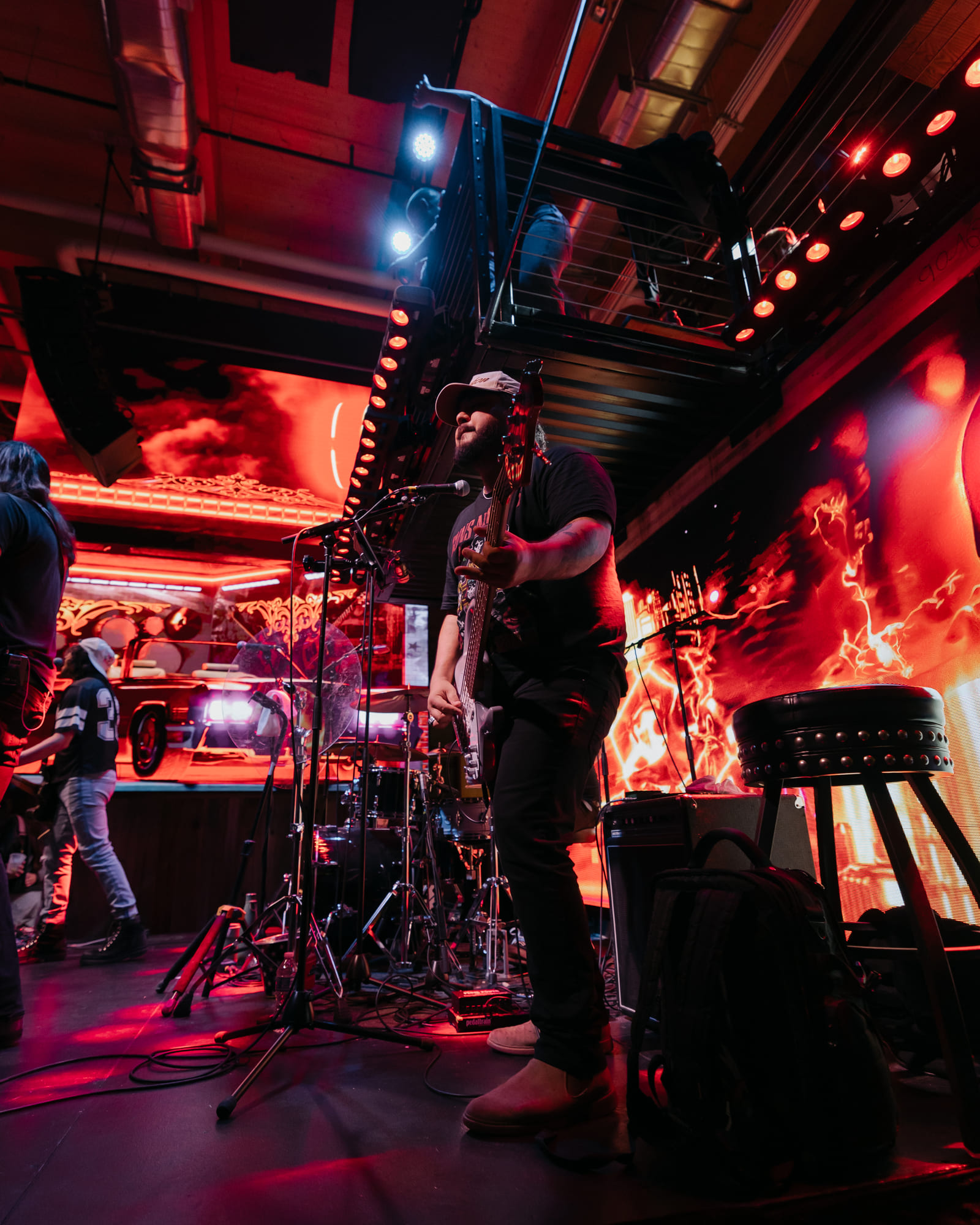 urrounded by dramatic red and orange lighting, Jellyroll is seen passionately playing guitar and performing on stage at Goodnight Nashville.