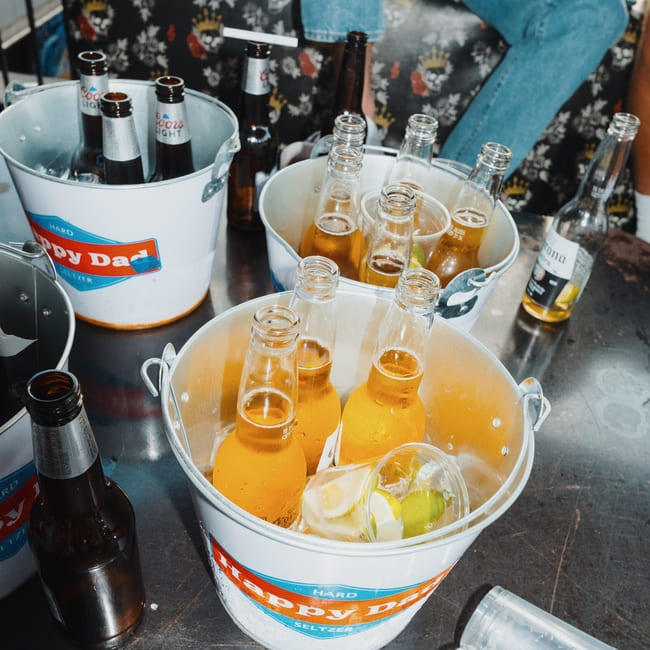 Buckets of chilled beer bottles with lime and lemon wedges on a bar table