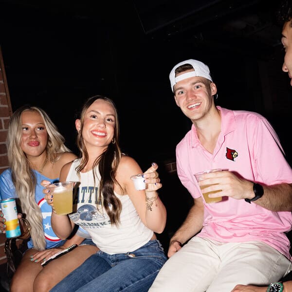 Three guests smiling and enjoying drinks together at Goodnight Nashville.